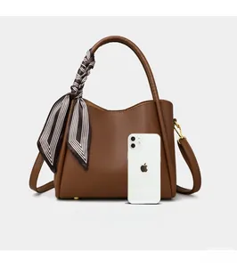 Brown litchi grain leather bucket bag size comparison with an iPhone 12 model