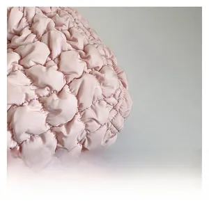 Primer plano del tejido acolchado rosa claro del bolso nube con textura plisada