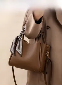 Brown lychee leather bucket bag with gold buckle and striped scarf detail on handle
