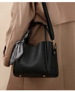 Close-up of black lychee leather tote bag with silk scarf and gold hardware accents