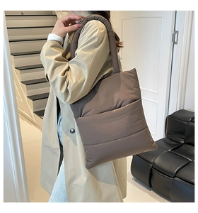 Brown padded puffer tote bag shown on a model with a stylish trench coat for autumn fashion