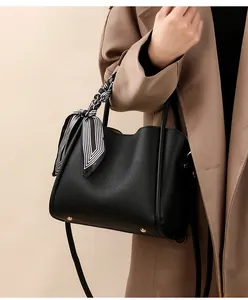 Detail of black lychee grain bucket bag with striped silk scarf handle and metal studs