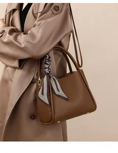 Detail of caramel leather bucket bag with lychee texture and striped silk scarf wrap