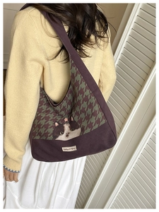 Detail of canvas tote bag with cat illustration and houndstooth pattern on shoulder