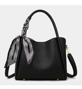 Detail of black pebbled leather bucket bag featuring a silk scarf on the handles