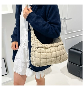 Detail view of beige quilted cloud bag showing the puffy texture and wide shoulder strap