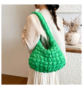 Detalle de bolso acolchado verde brillante con tejido de burbujas y cremallera plateada