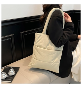 Close-up of cream beige quilted puffer tote bag on model showing soft padded texture