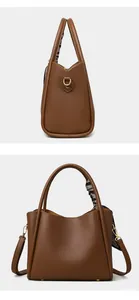 Detail of dark brown pebble leather handbag featuring gold hardware and silk scarf handle
