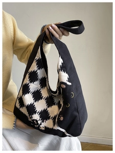 Detail of checkered canvas tote bag with cute black cat design held by a model