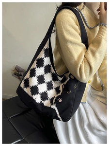 Detail of checkered canvas tote bag featuring yellow cat eyes and cute paw embroidery