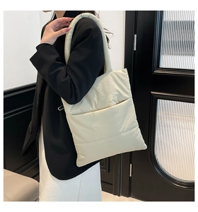 Close-up of beige quilted puffy tote bag styled with a professional black blazer