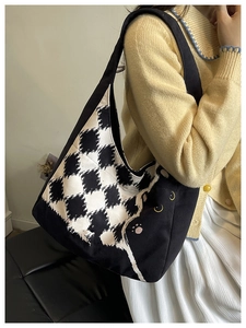 Detail of canvas tote bag featuring black cat illustration and checkered pattern on shoulder