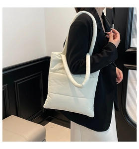 Close-up of a white puffy quilted tote bag made of glossy nylon on a model shoulder