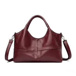 Detail view of wine red leather tote bag with cross stitching and detachable shoulder strap
