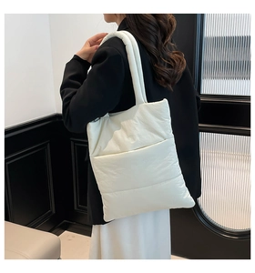 Side view of white quilted puffer tote bag worn by model in minimalist indoor setting