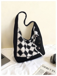 Detail of canvas tote bag with black cat illustration and checkered pattern next to a laptop