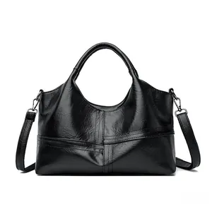Detail of cross-stitched stitching and soft black leather texture on a large tote bag