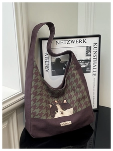 Close-up of canvas tote bag featuring green houndstooth pattern and cute cat illustration