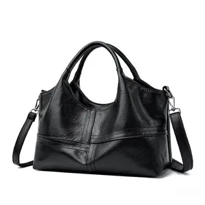 Detail of black leather handbag with crisscross stitching and detachable shoulder strap