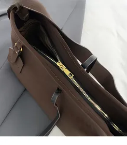 Detail of high-quality gold zipper and striped lining on dark brown leather tote bag