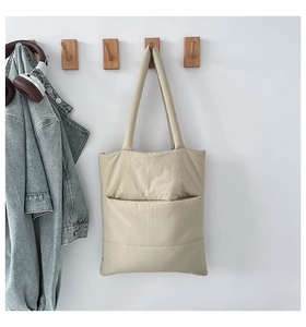 Close-up of off-white quilted puffer tote bag in soft nylon hanging on a wooden hook
