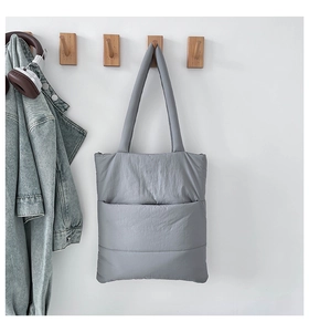 Detailed view of a grey quilted tote bag hanging on a hook with a casual jacket