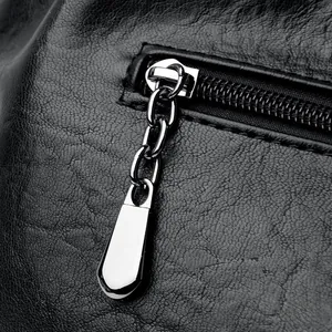 Macro view of silver zipper pull and lychee texture on black leather handbag