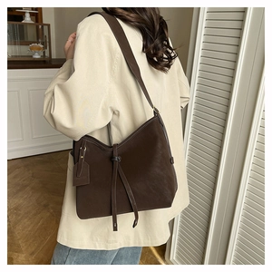 Detail of a brown Hobo tote bag with contrast stitching and decorative brand tag