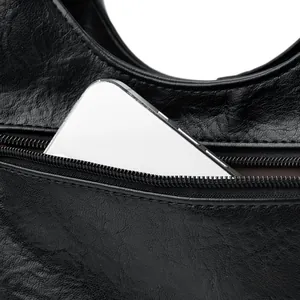 Detail of the hidden back zipper pocket on black leather bag with a smartphone inside