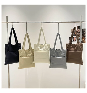 Five puffer quilted tote bags in various colors hanging on a rack for display