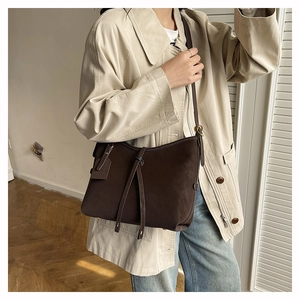 Detail of dark brown matte tote bag with long leather straps and side logo tag
