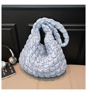 Detail der hellblauen gesteppten Puffer-Tasche mit Bubble-Textur auf einer Lederbank