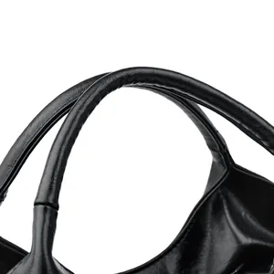Macro detail of the smooth black leather handle with reinforced stitching on women handbag