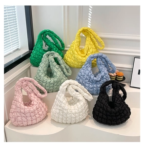 Bolsos tote acolchados en siete colores, incluidos verde y rosa, expuestos en un estudio