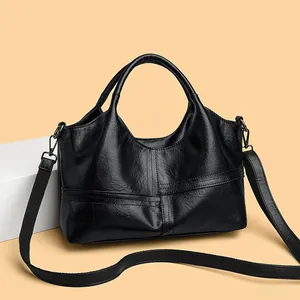 Close-up of black soft leather handbag showing cross-stitch detail and texture