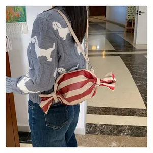 Detailed view of a candy-shaped crossbody bag with red and white stripes in a lifestyle setting