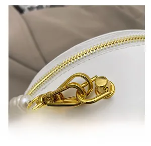 Detail of premium gold clasp with pearl strap and smooth white leather stitching