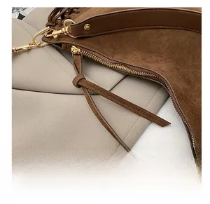 Detail of smooth gold zipper and brown suede texture on a vintage crescent shoulder bag