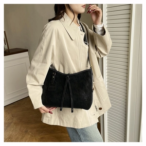 Detail of black suede tote bag featuring long tassel drawstrings and fashion tag