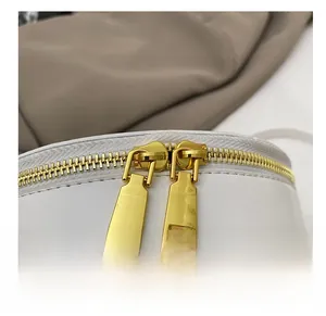 Detailed close-up of smooth gold dual zippers on a premium white leather crossbody bag