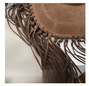 Detail of a brown suede tote bag featuring long woven tassels in bohemian style