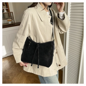 Detail of black matte leather tote bag with long tassel drawstring and fashion tag