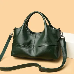 Close-up of a dark green faux leather handbag with stitching details and metal hardware