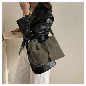Detail of grey-green suede tote bag with a fashion tag on a female model
