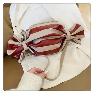 Detail view of red and white striped candy-shaped crossbody bag with gold-tone zipper closure