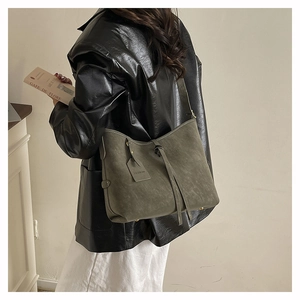 Detailed close-up of dark green suede tote bag with slim straps and fashion tag
