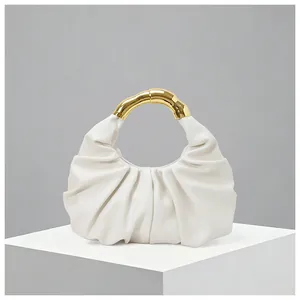 Detail of creamy white ruched cloud bag featuring a unique gold metallic handle texture