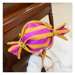 Detail of candy-shaped crossbody bag featuring yellow and purple stripes with leather texture