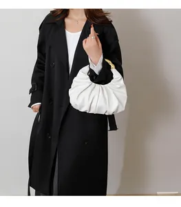 Close-up of white ruched cloud bag featuring elegant gold ring handles and soft textures